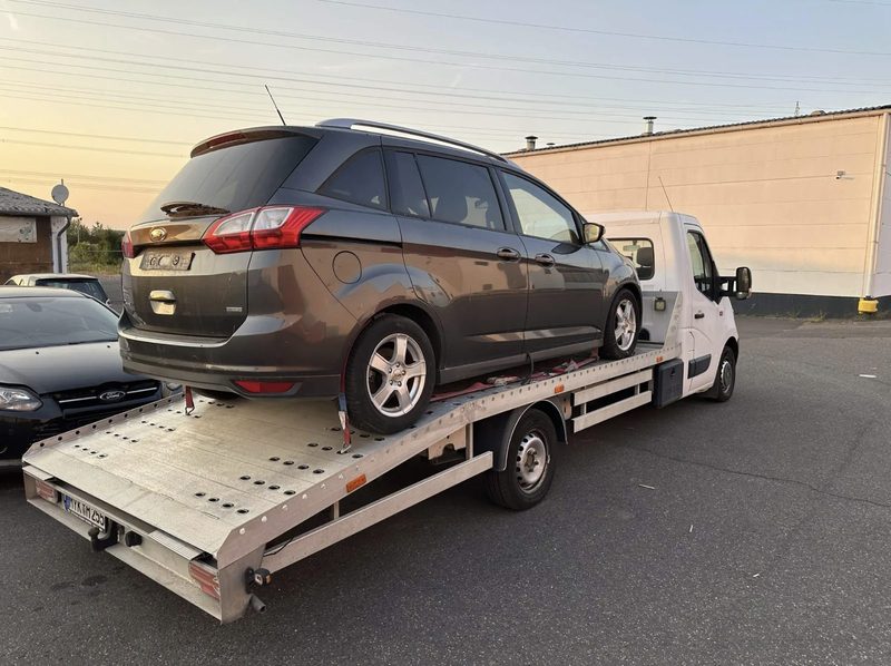 Angekaufter Ford C-Max verzurrt auf dem Transporter — bereit zur Abfahrt